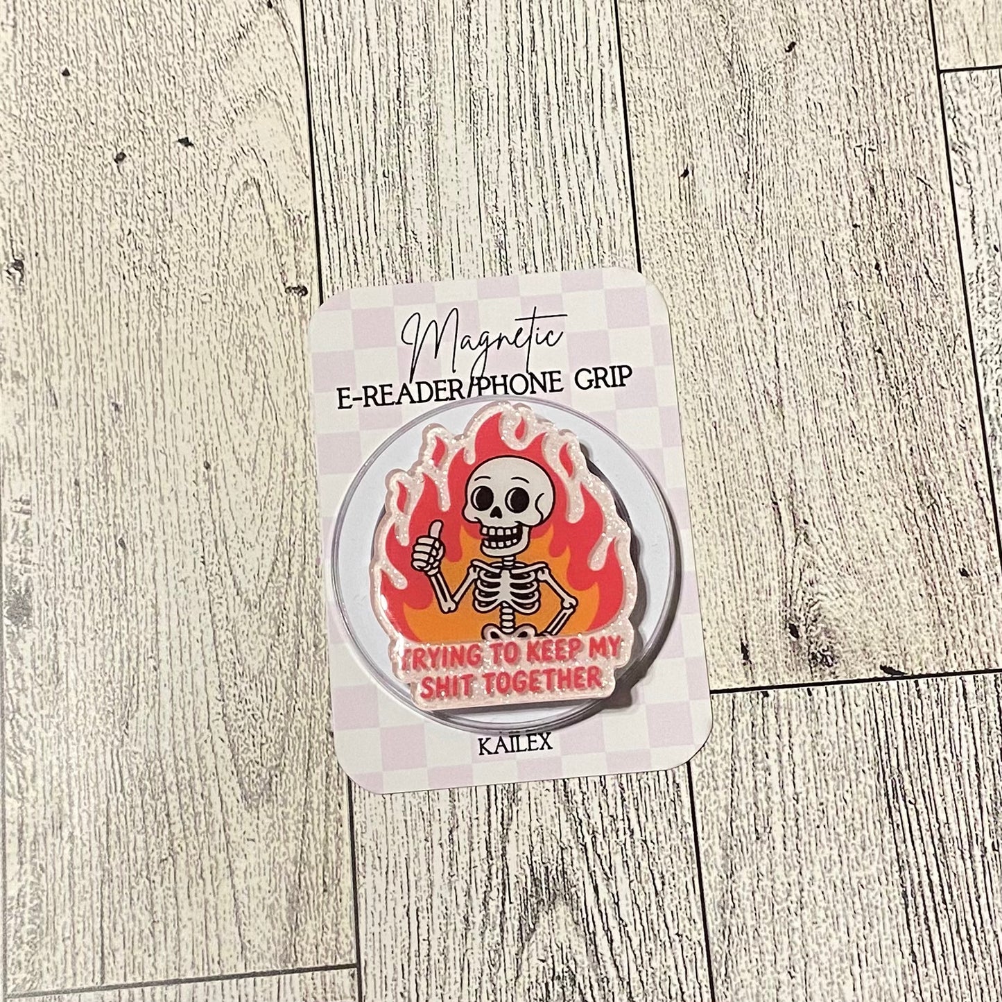 Magnetic e-reader/phone grip with skeleton design on a wooden surface