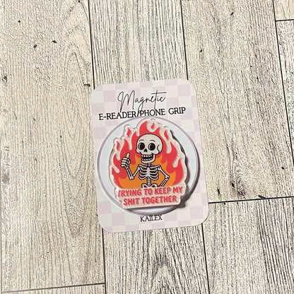 Magnetic e-reader/phone grip with skeleton design on a wooden surface