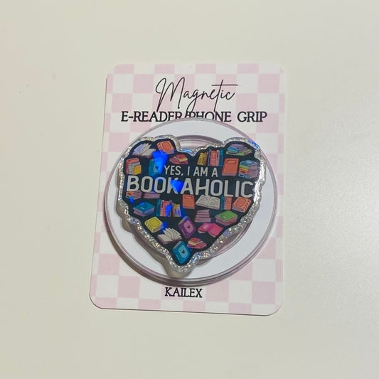 Heart-shaped magnetic e-reader phone grip with 'Bookaholic' text on a checkered card, brand 'KAILEX' visible.