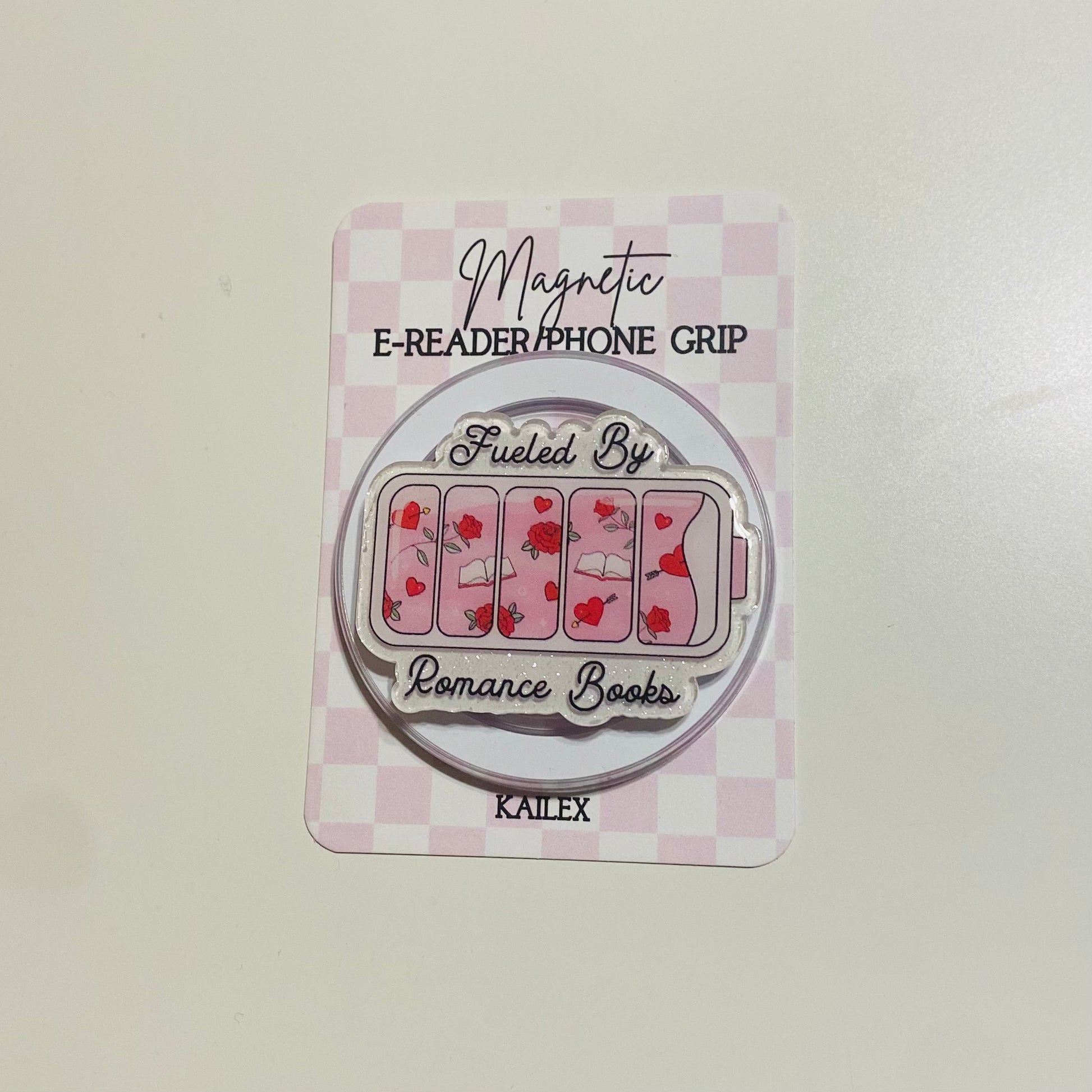 Magnetic e-reader phone grip with 'Fueled By Romance Books' design on a checkered background