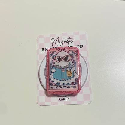 Magnetic e-reader book grip with cartoon character on a checkered card, brand 'KALEX' visible