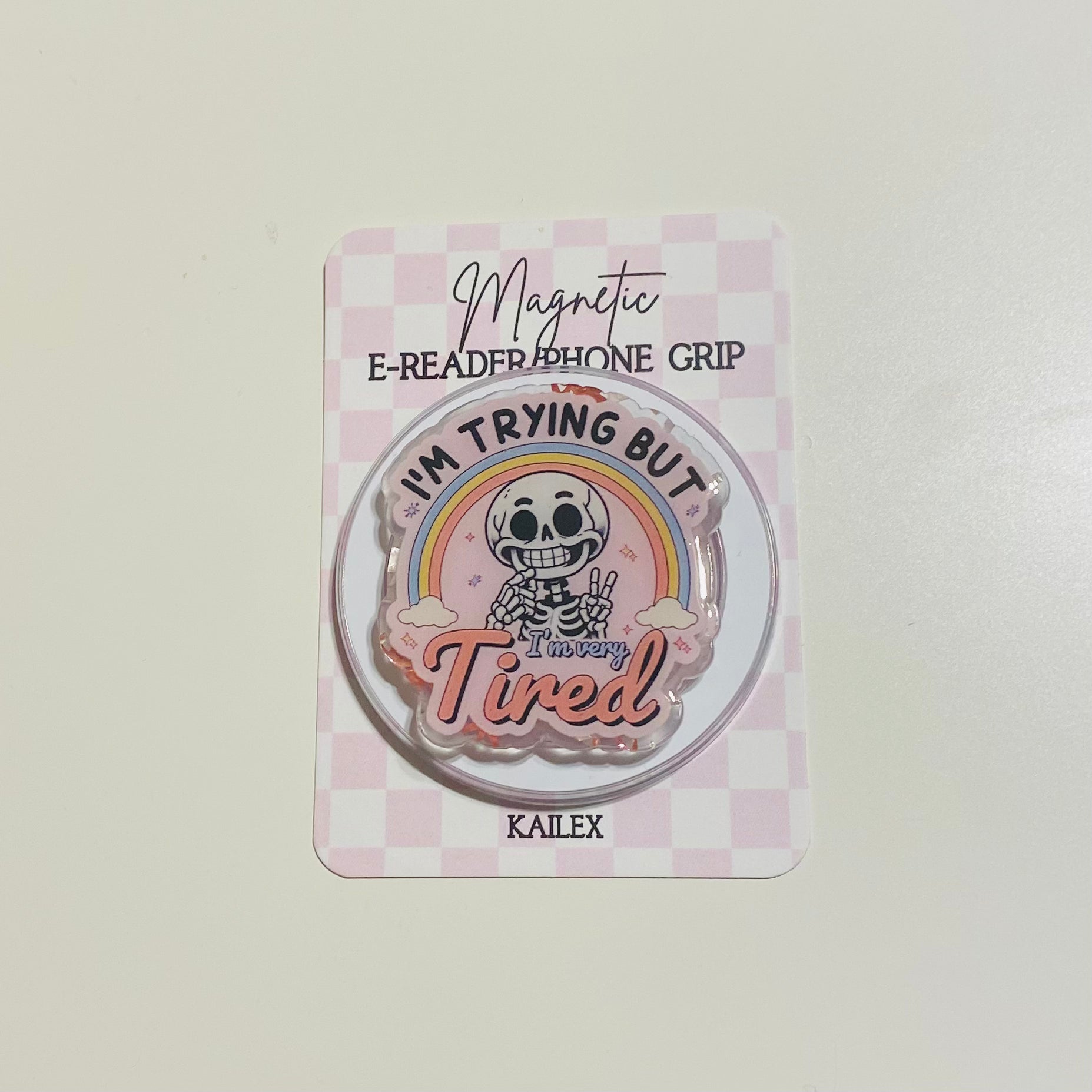 Magnetic e-reader phone grip with cartoon character and text on a checkered background