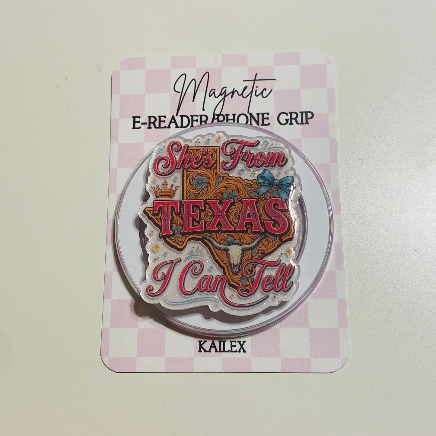 Magnetic e-reader phone grip with 'She's from Texas I can tell' design on a checkered card
