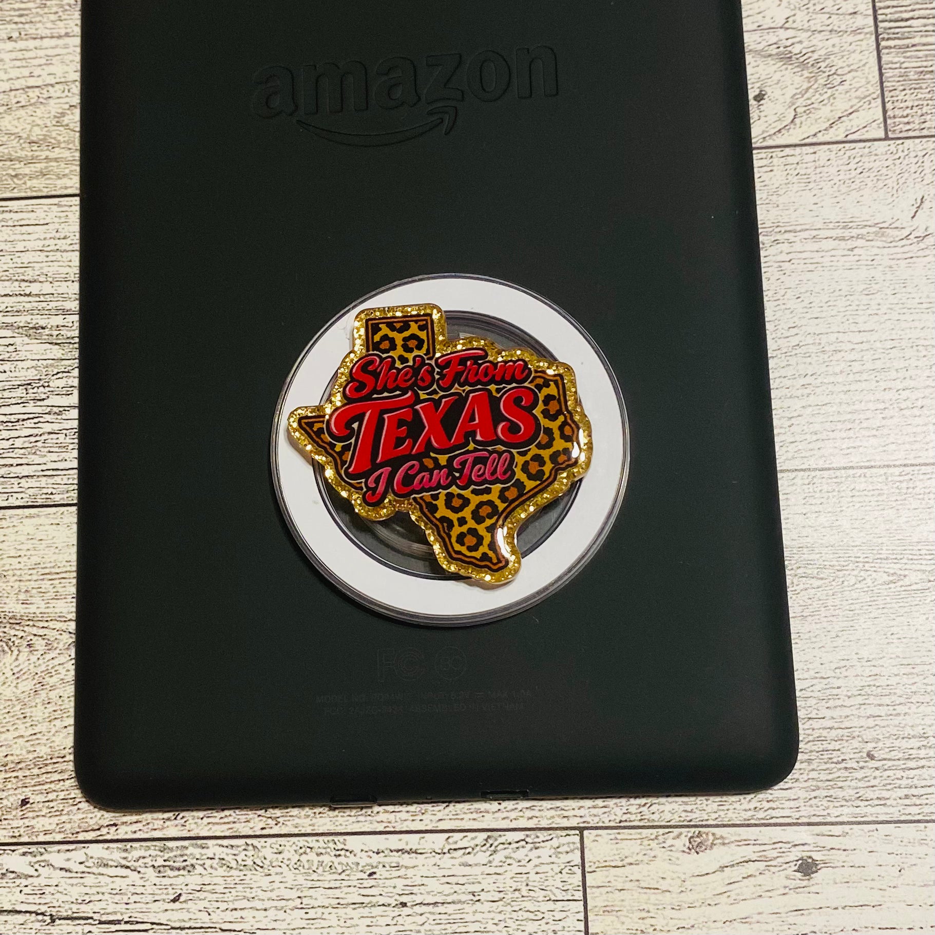 Pin with 'She's from Texas, I can tell' text on a black surface with Amazon logo
