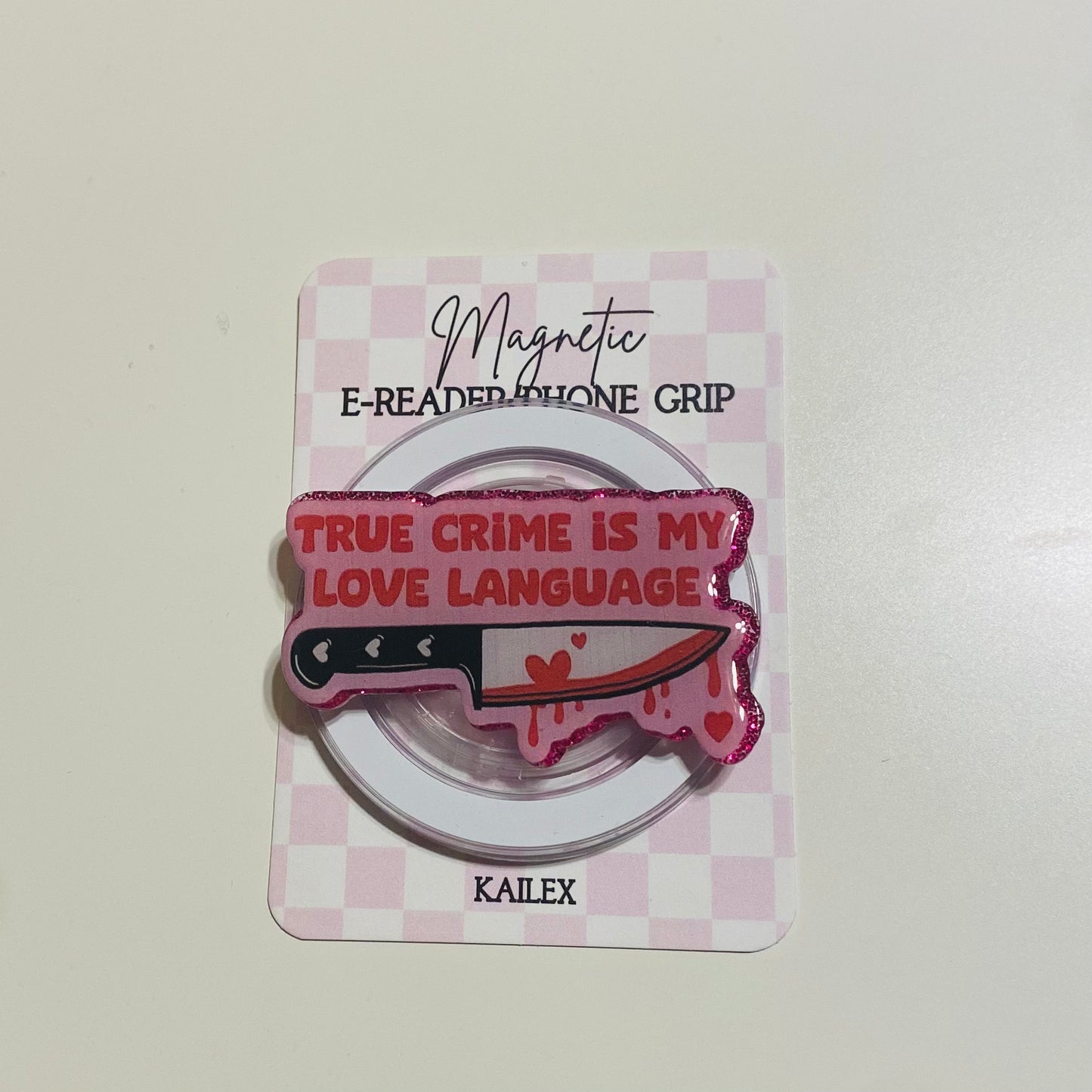 Magnetic e-reader phone grip with knife design and text on a checkered card