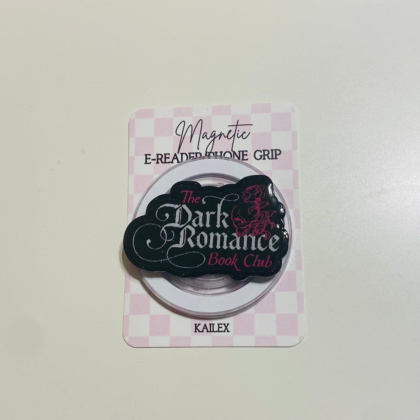 Magnetic e-reader phone grip with 'The Dark Romance Book Club' branding on a checkered background