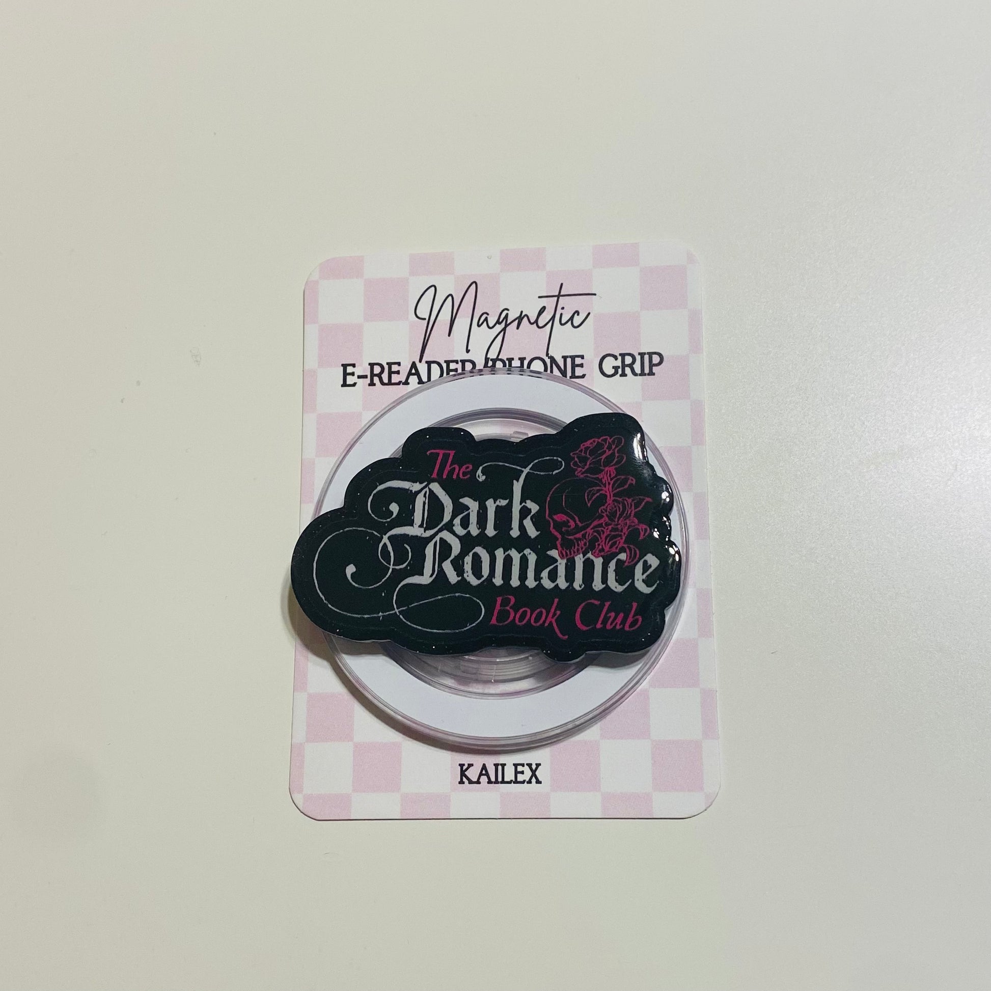 Magnetic e-reader phone grip with 'The Dark Romance Book Club' branding on a checkered background