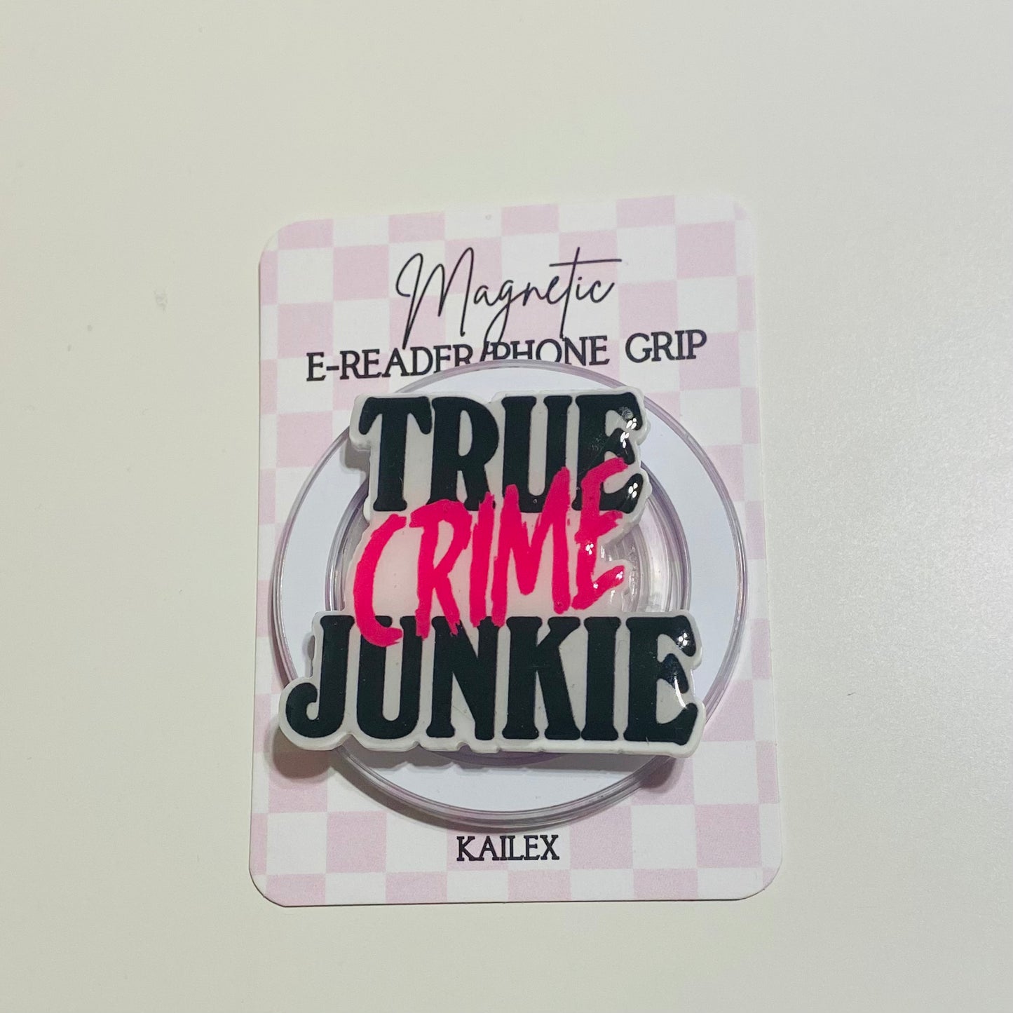 Magnetic e-reader phone grip with 'True Crime Junkie' text on a checkered background