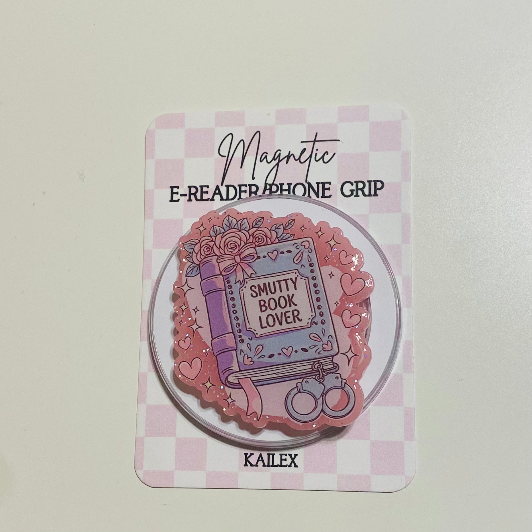 Magnetic e-reader phone grip with decorative design on a checkered card