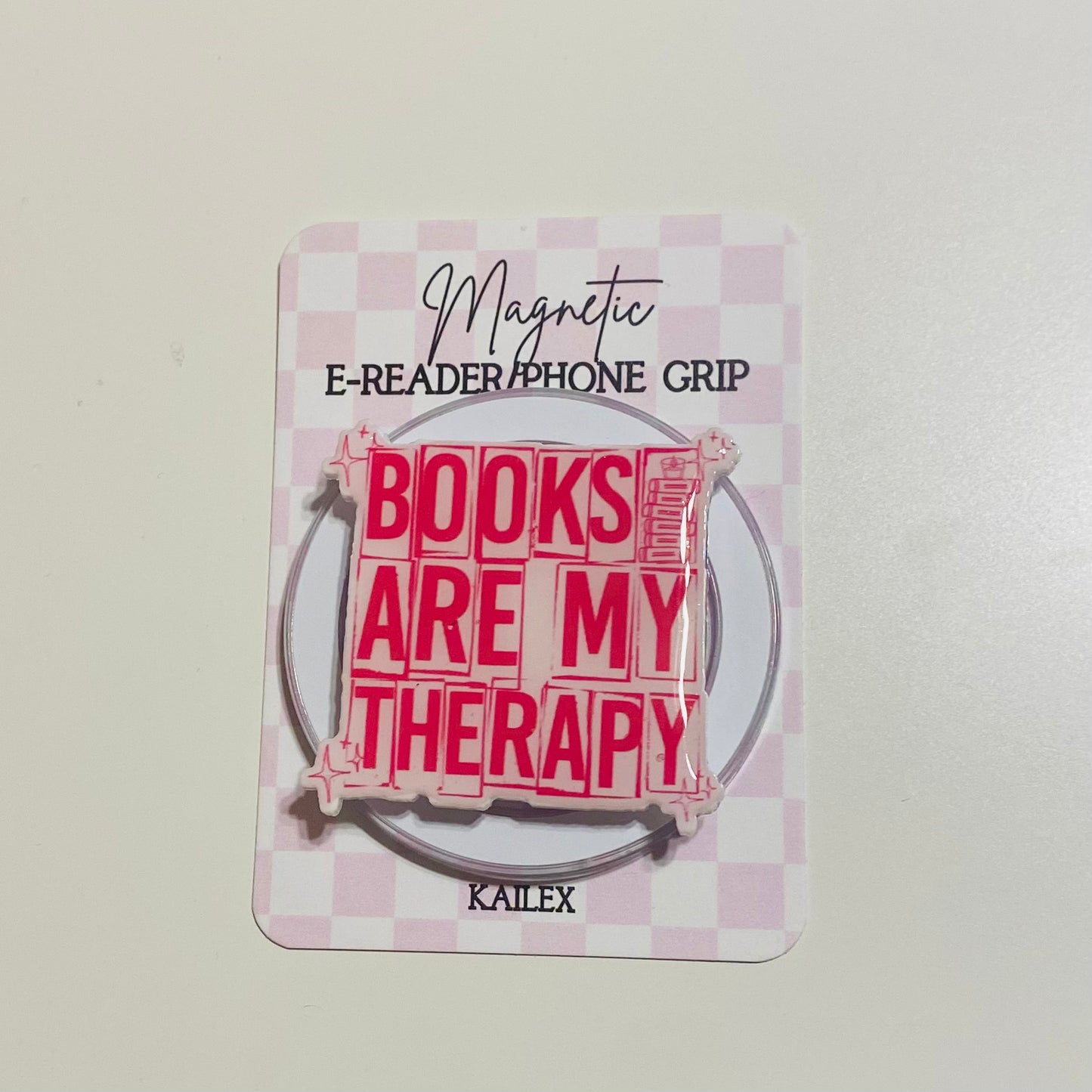 Magnetic e-reader phone grip with 'Books are my therapy' text on a checkered background