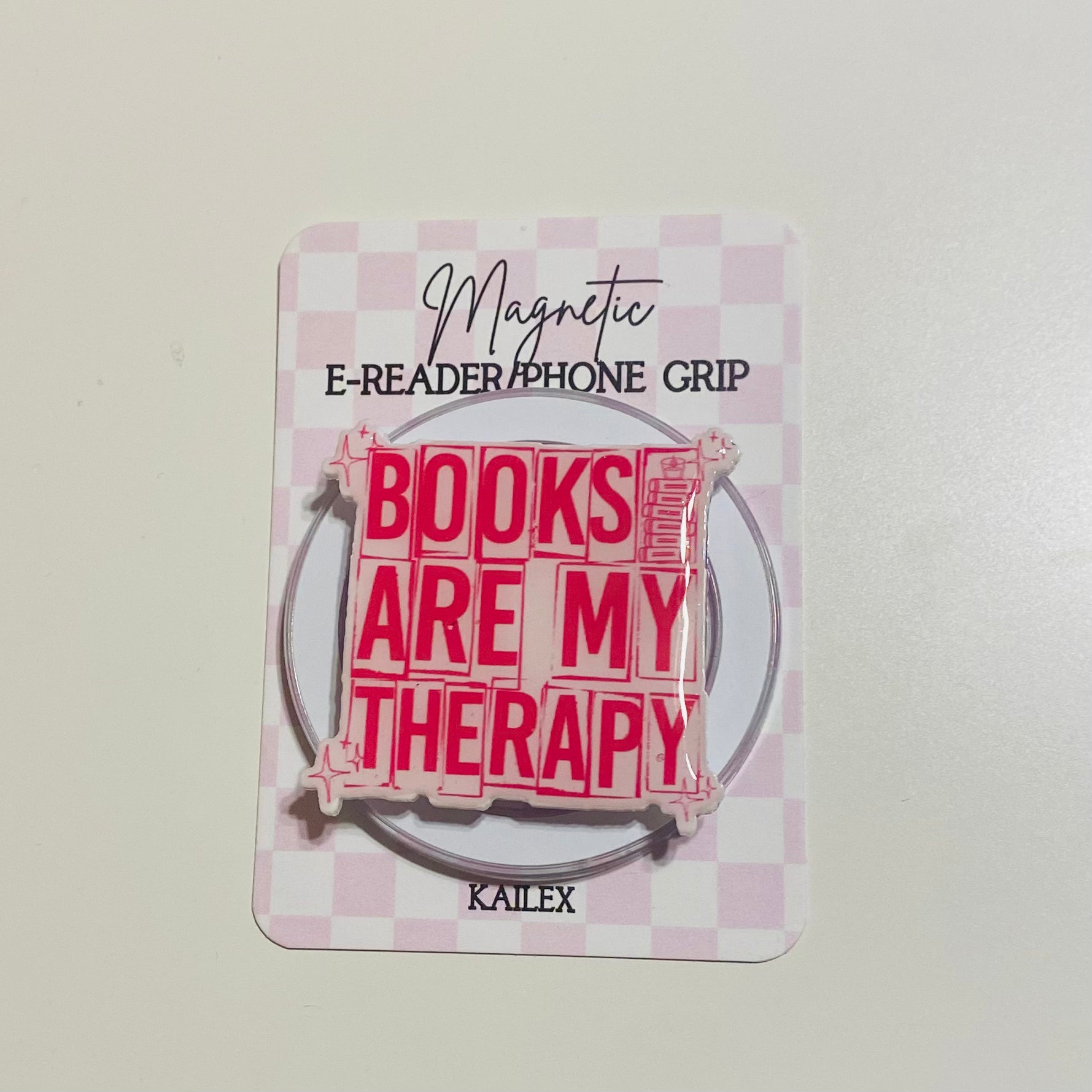 Magnetic e-reader phone grip with 'Books are my therapy' text on a checkered background