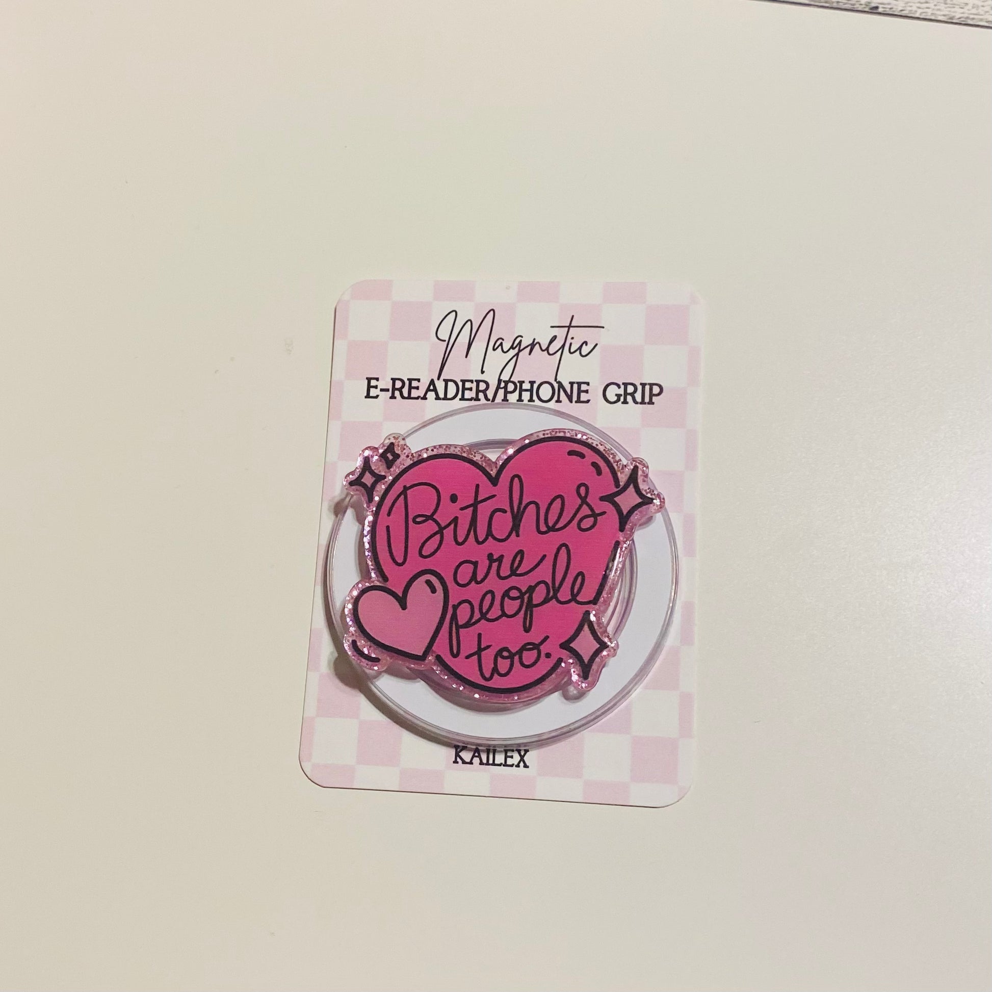 Pink magnetic e-reader phone grip with text on a checkered card