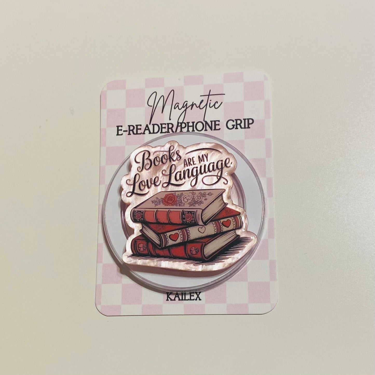 Magnetic e-reader phone grip with 'Books are my love language' design on a checkered card