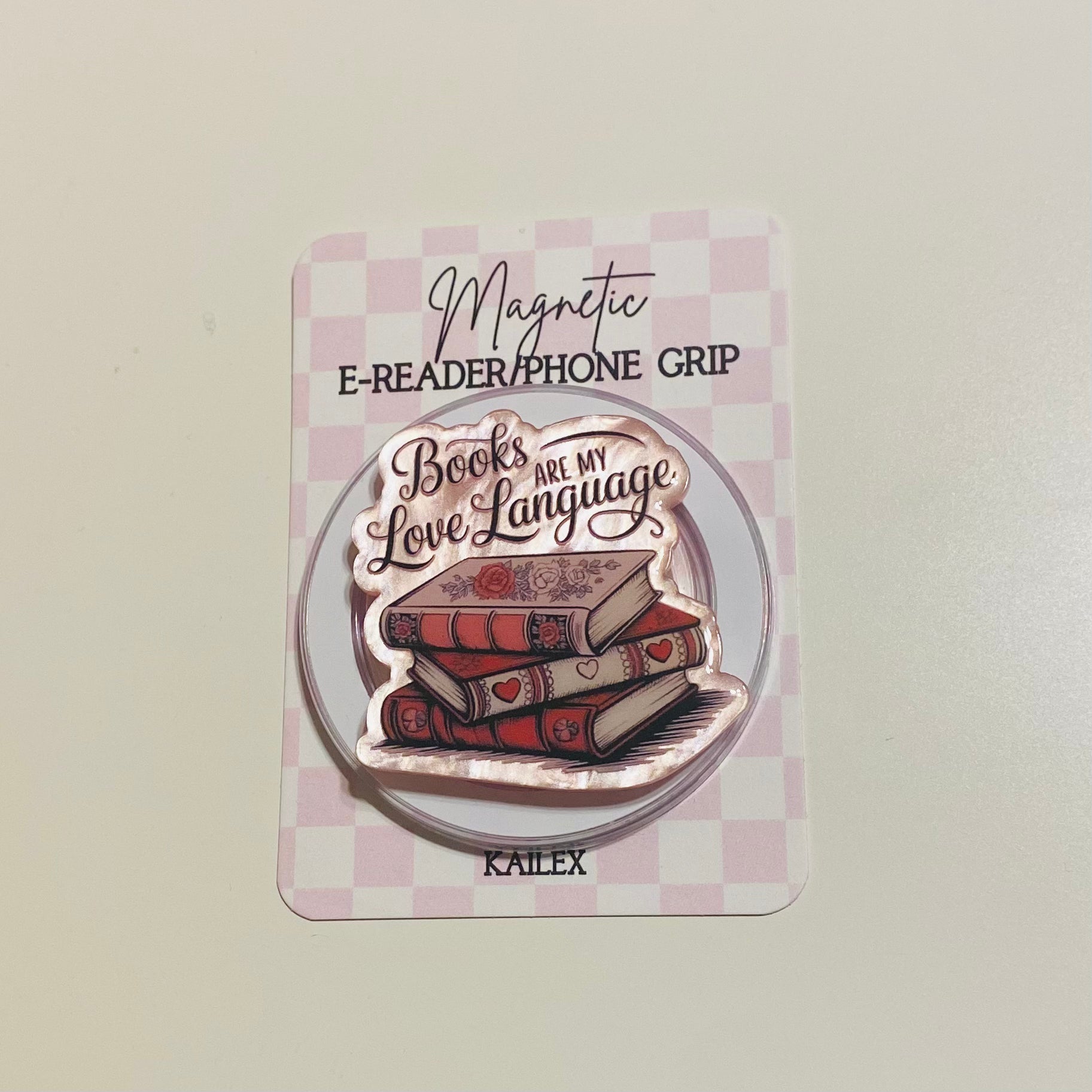 Magnetic e-reader phone grip with 'Books are my love language' design on a checkered card