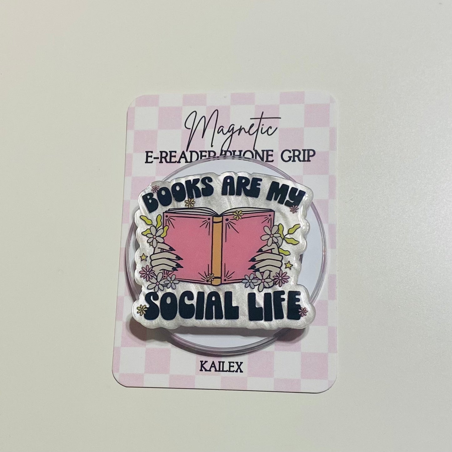 Magnetic e-reader phone grip with 'Books are my social life' design on a checkered background