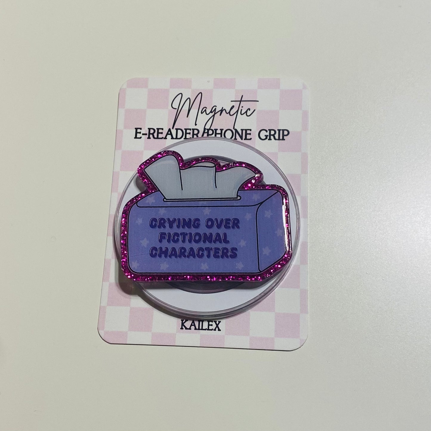 Magnetic e-reader phone grip with purple design and text on a checkered card