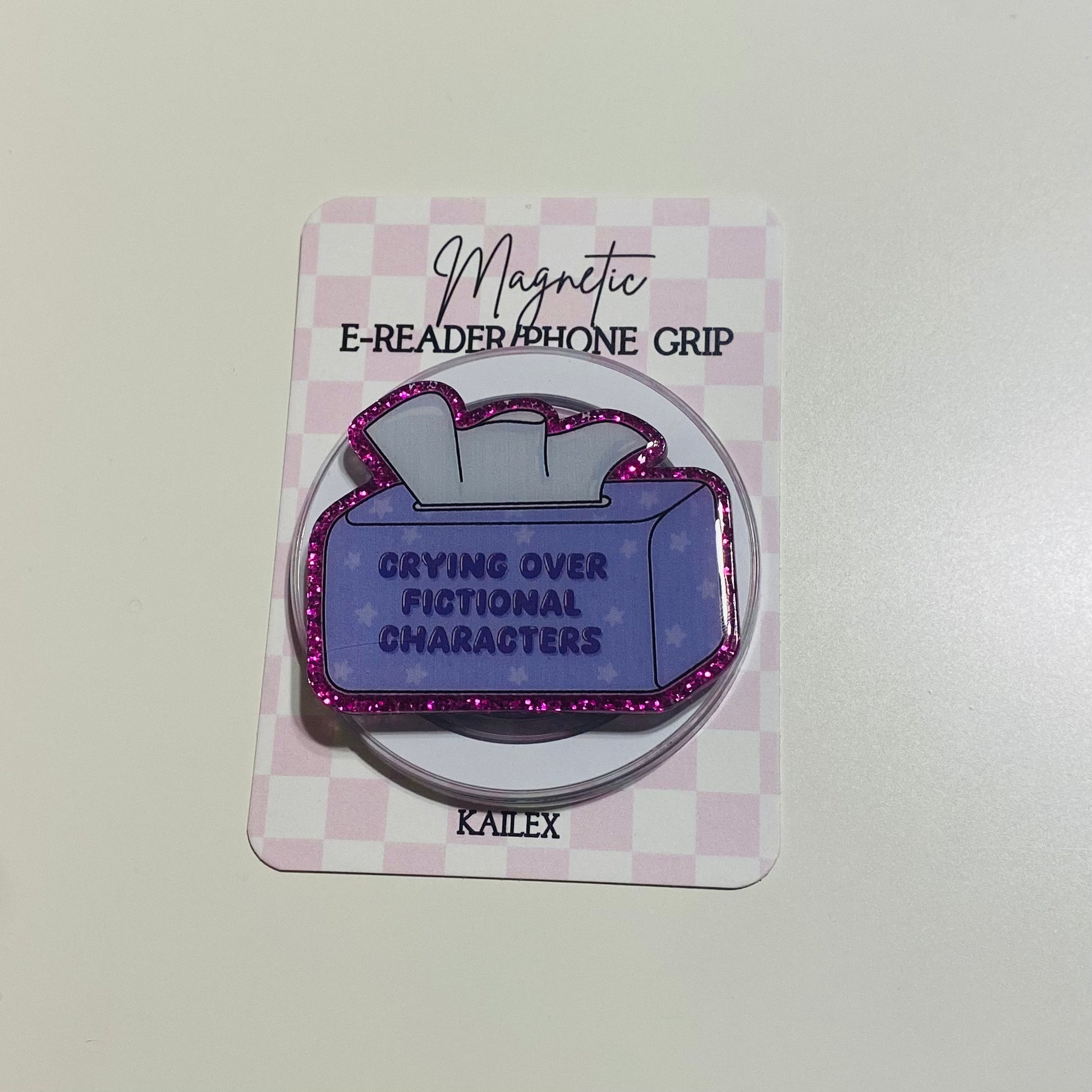 Magnetic e-reader phone grip with purple design and text on a checkered card