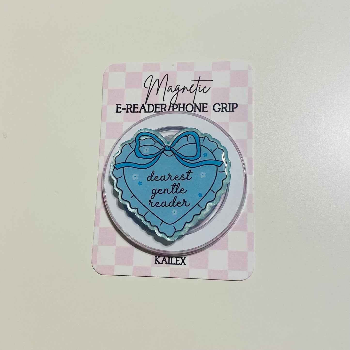 Blue heart-shaped e-reader phone grip with bow design on a checkered card, brand 'KALEX' visible