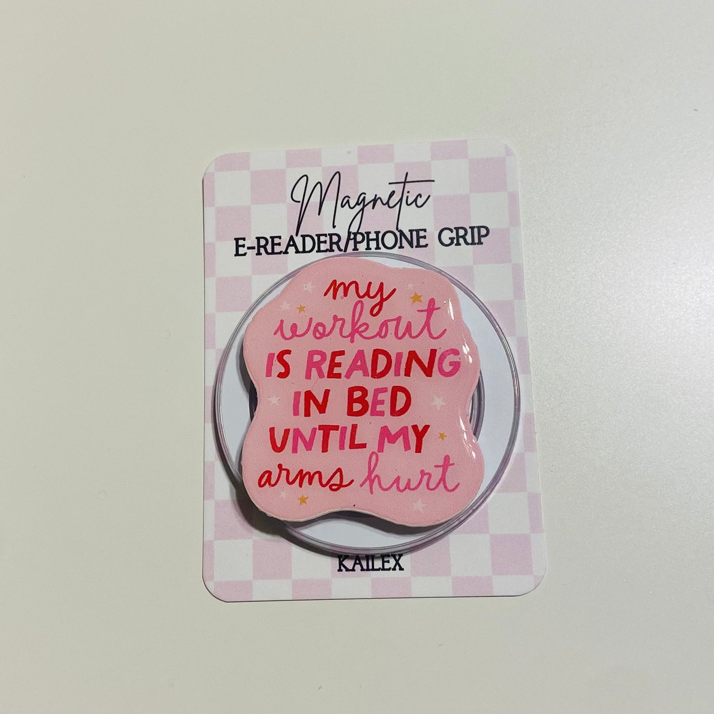 Magnetic e-reader/phone grip with pink design and text on a checkered background