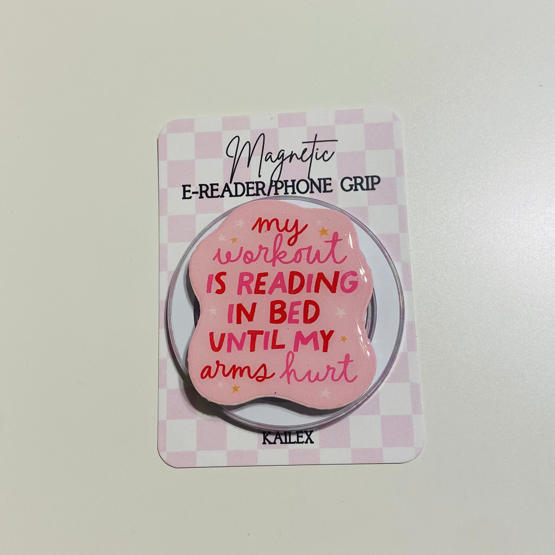Magnetic e-reader/phone grip with pink design and text on a checkered background