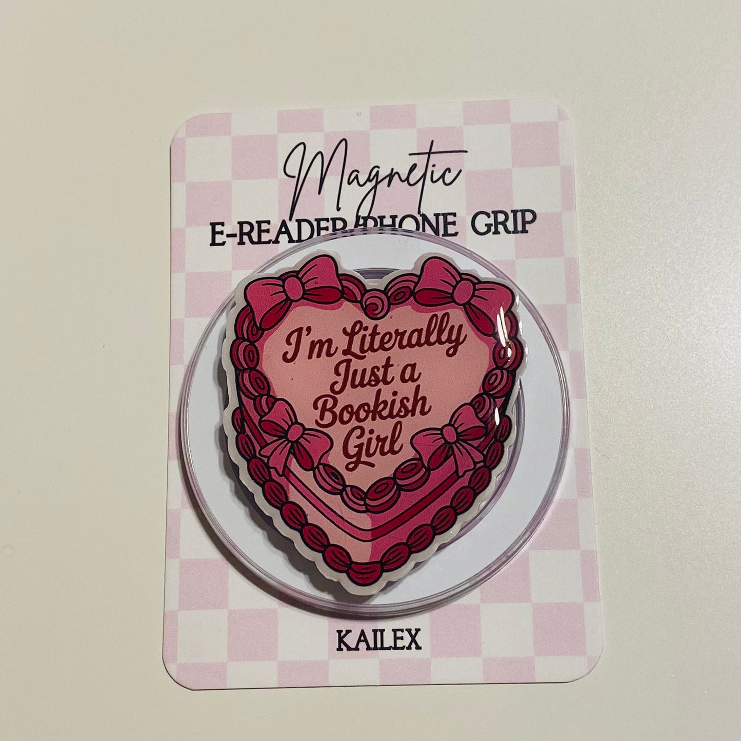 Heart-shaped magnetic e-reader phone grip with text on a checkered background