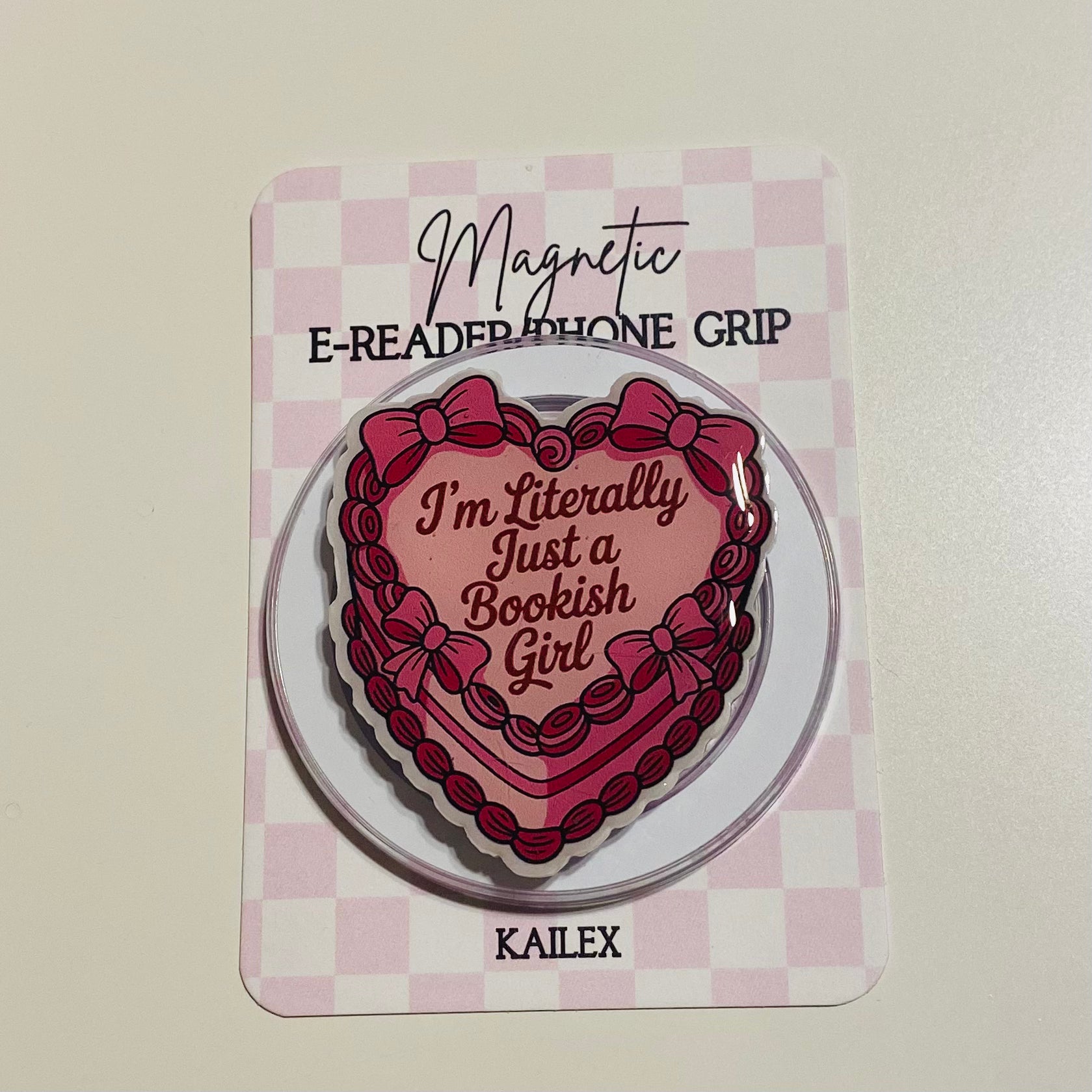 Heart-shaped magnetic e-reader phone grip with text on a checkered background