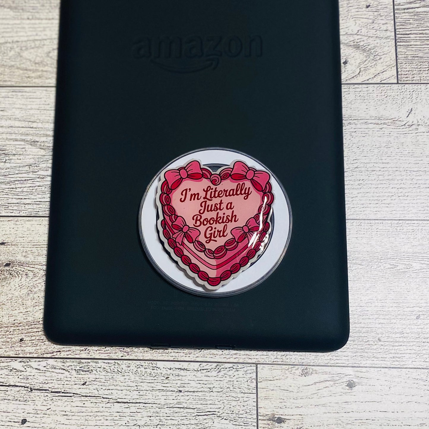 Heart-shaped magnetic e-reader phone grip with text on a checkered background