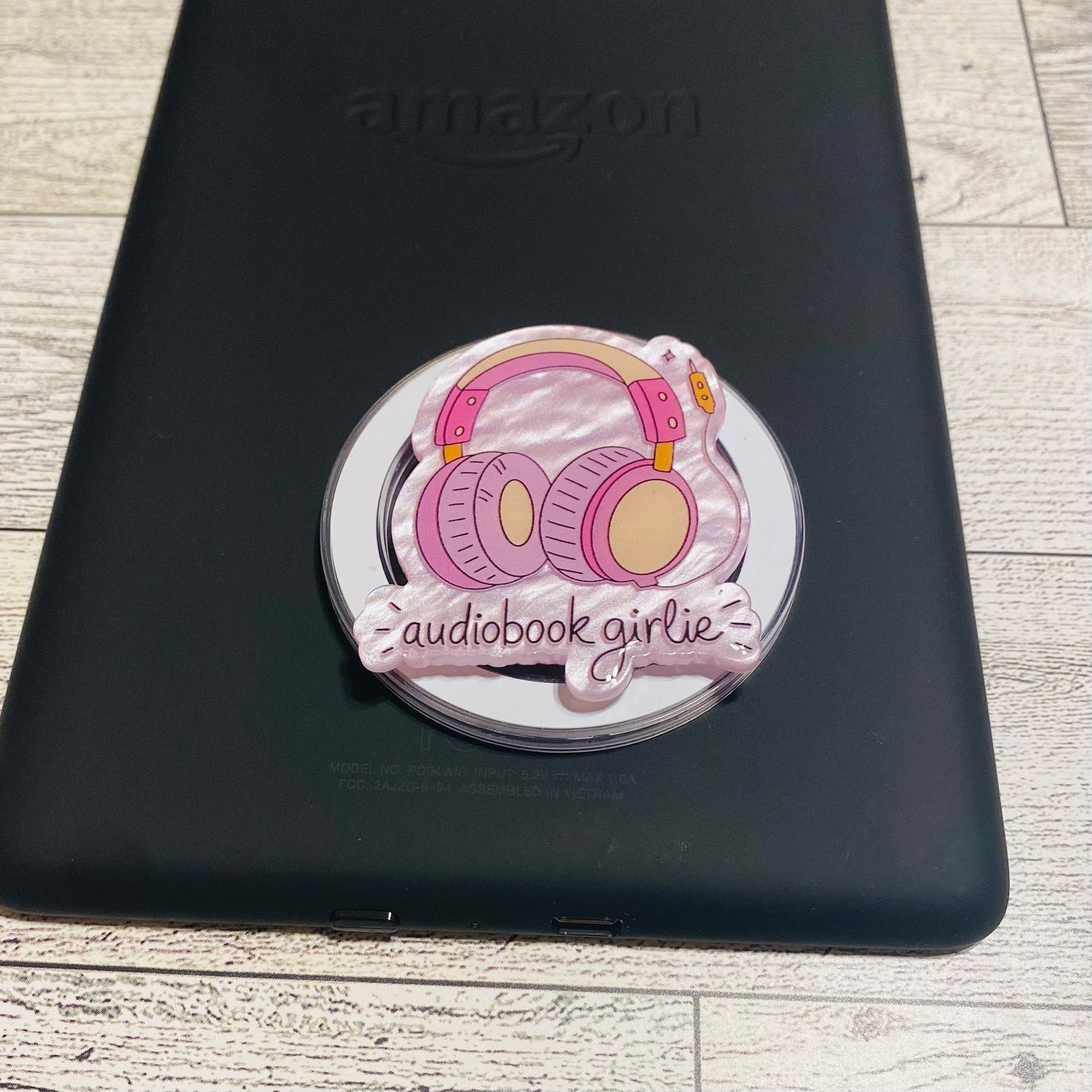 Magnetic e-reader phone grip with headphone design on a checkered background
