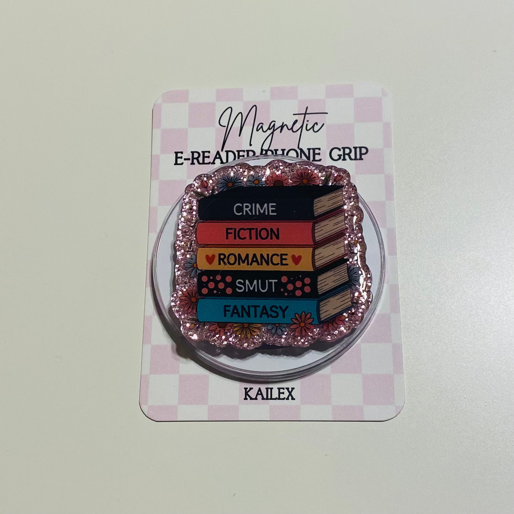 Magnetic e-reader phone grip with book genre text on a checkered card, brand 'KAILEX' visible
