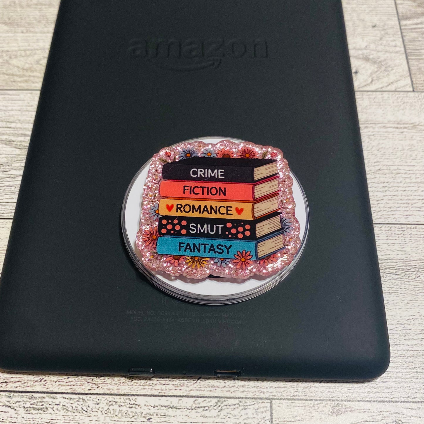 Magnetic e-reader phone grip with book genre text on a checkered card, brand 'KAILEX' visible

