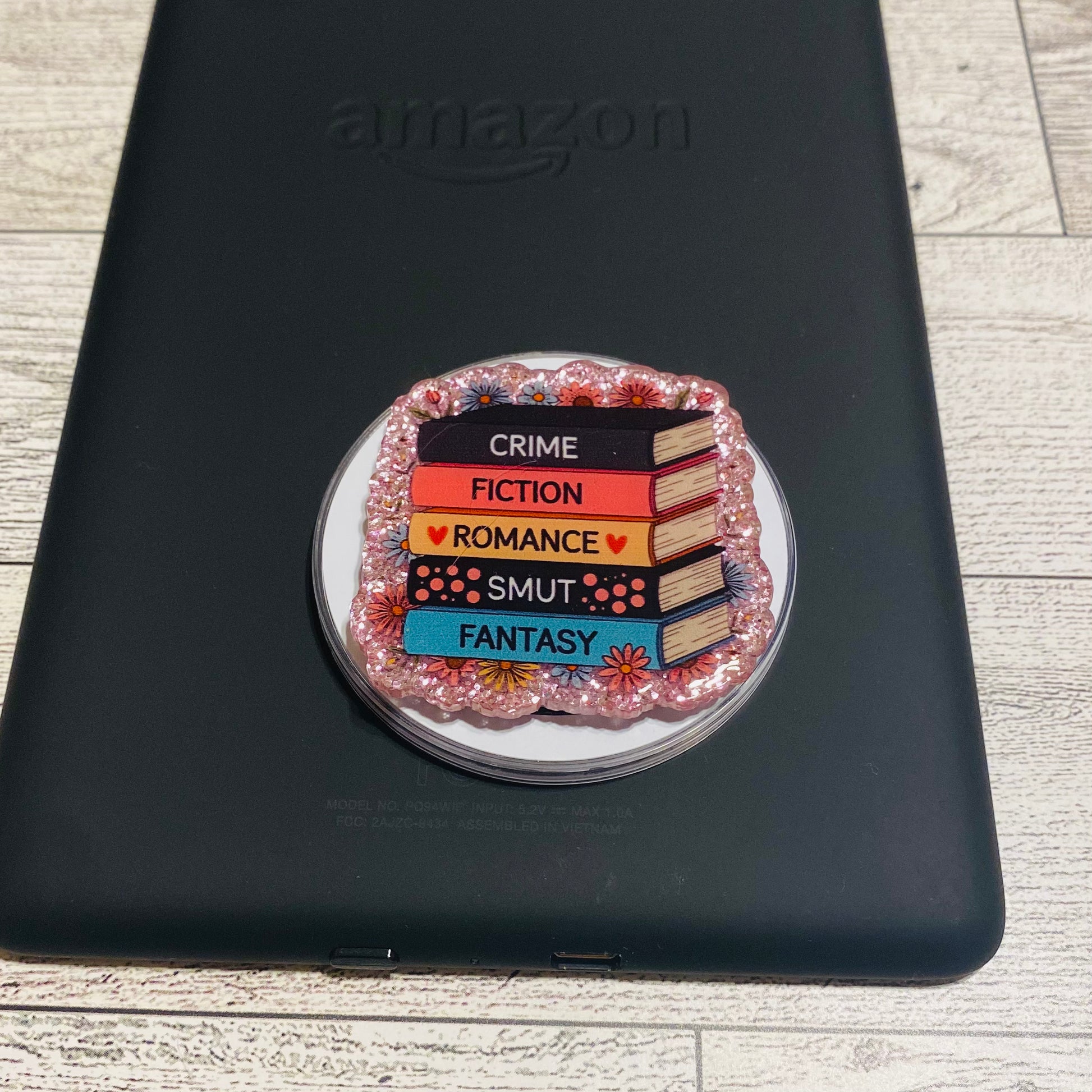 Magnetic e-reader phone grip with book genre text on a checkered card, brand 'KAILEX' visible

